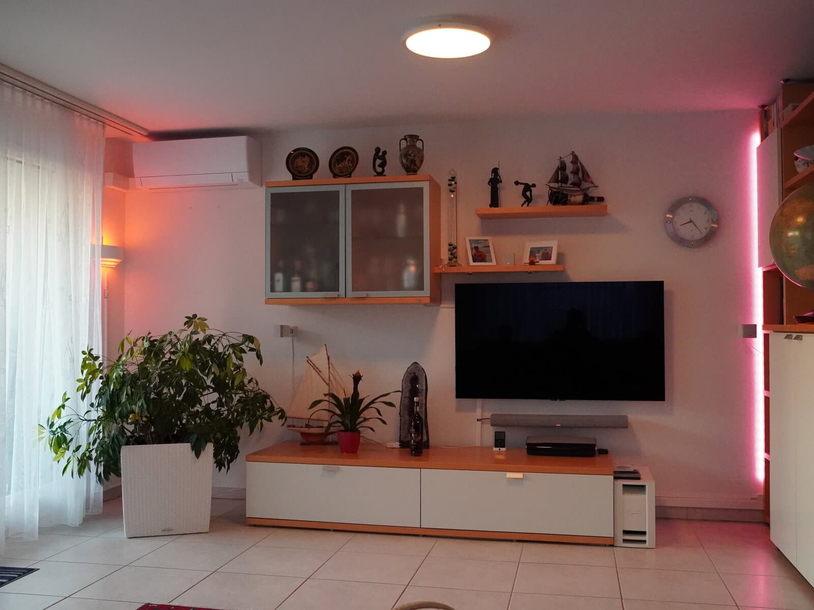 Wohnzimmer nach der Installation - Szene mit magentafarbenem Ambientelicht hinter dem Regal